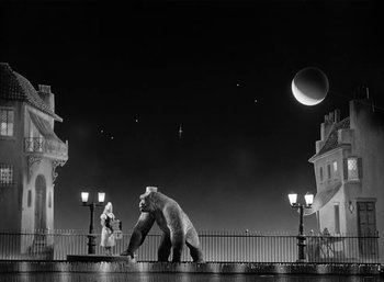 Movie still from “Mighty Joe Young” (1949), directed by Ernest B. Schoedsack – A woman standing next to a bear on top of a fence; Extreme Wide shot, Low angle