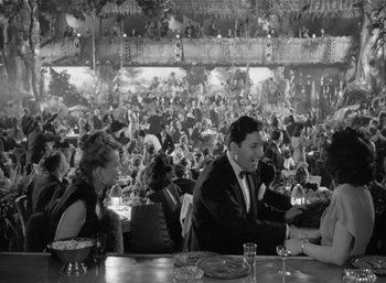 Movie still from “Mighty Joe Young” (1949), directed by Ernest B. Schoedsack – A black and white photo of people sitting at a table; Wide shot, High angle
