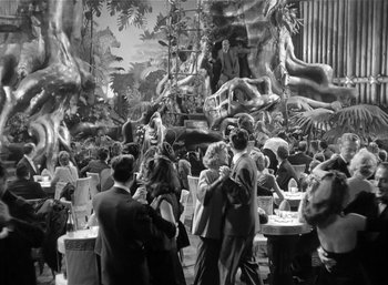Movie still from “Mighty Joe Young” (1949), directed by Ernest B. Schoedsack – A black and white photo of people at a party; Extreme Wide shot, High angle