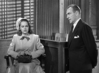 Movie still from “Mighty Joe Young” (1949), directed by Ernest B. Schoedsack – An old photo of a man and a woman sitting in a courtroom; Medium shot, Low angle
