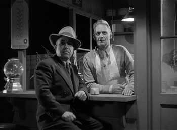 Movie still from “Mighty Joe Young” (1949), directed by Ernest B. Schoedsack – Two men in suits and hats are sitting on a bench; Medium shot, Low angle