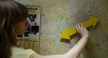 Movie still from “Mood Indigo” (2013), directed by Michel Gondry – A person looking at a map with a yellow arrow pointing to it; Extreme Close Up shot, Overhead angle