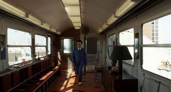 A man in a blue suit is walking down a train