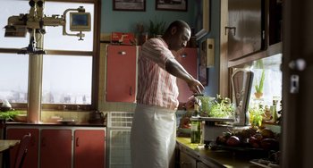 Movie still from “Mood Indigo” (2013), directed by Michel Gondry – A man standing in a kitchen preparing a salad; Medium shot, Low angle