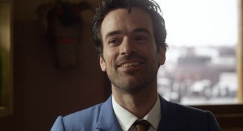 Movie still from “Mood Indigo” (2013), directed by Michel Gondry – A person wearing a suit and smiling; Close Up shot, Over the shoulder angle