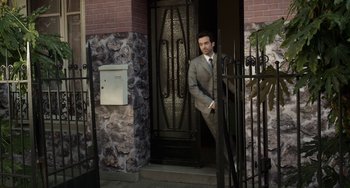 Movie still from “Mood Indigo” (2013), directed by Michel Gondry – A man standing in front of a door way; Wide shot, High angle