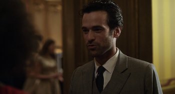 Movie still from “Mood Indigo” (2013), directed by Michel Gondry – A man wearing a suit and tie in front of a wall; Close Up shot, Over the shoulder angle