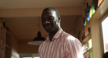 Movie still from “Mood Indigo” (2013), directed by Michel Gondry – A man in a striped shirt smiling for the camera; Close Up shot, Over the shoulder angle