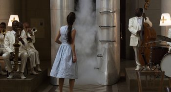 Movie still from “Mood Indigo” (2013), directed by Michel Gondry – A woman standing in front of a large metal tank; Medium shot, Low angle