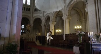 Movie still from “Mood Indigo” (2013), directed by Michel Gondry – A man flying a kite inside a church; Extreme Wide shot, Low angle