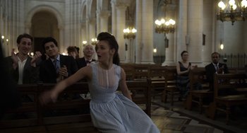 Movie still from “Mood Indigo” (2013), directed by Michel Gondry – A woman in a blue and white dress sitting on a bench in a church; Medium shot, Over the shoulder angle