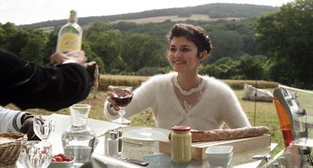 Movie still from “Mood Indigo” (2013), directed by Michel Gondry – A woman sitting at a table holding a glass of wine; Medium shot, High angle