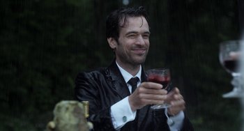 Movie still from “Mood Indigo” (2013), directed by Michel Gondry – A man holding a wine glass in his hands; Medium shot, Over the shoulder angle