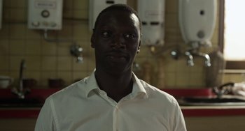 Movie still from “Mood Indigo” (2013), directed by Michel Gondry – A man wearing a white shirt in a kitchen; Close Up shot, Over the shoulder angle