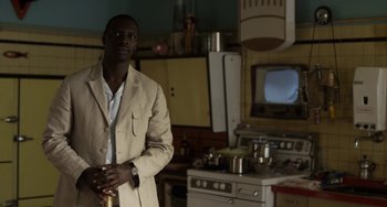 Movie still from “Mood Indigo” (2013), directed by Michel Gondry – A man standing in a kitchen next to an oven; Medium shot, Over the shoulder angle