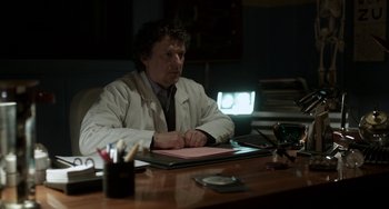 Movie still from “Mood Indigo” (2013), directed by Michel Gondry – A man sitting at a desk in front of a laptop computer; Medium shot, Low angle
