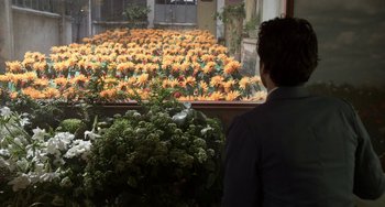 Movie still from “Mood Indigo” (2013), directed by Michel Gondry – A man looking at a large display of flowers; Wide shot, Over the shoulder angle