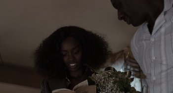 Movie still from “Mood Indigo” (2013), directed by Michel Gondry – A woman sitting at a table reading a book; Close Up shot, Over the shoulder angle