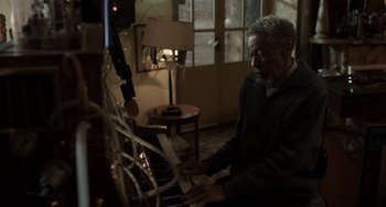 Movie still from “Mood Indigo” (2013), directed by Michel Gondry – An older man sitting at a piano in a living room; Medium shot, High angle