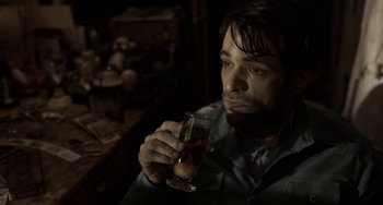 Movie still from “Mood Indigo” (2013), directed by Michel Gondry – A man sitting in a dark room holding a glass of wine; Close Up shot, High angle