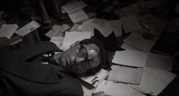 Movie still from “Mood Indigo” (2013), directed by Michel Gondry – A man in a suit laying on the ground with papers; Close Up shot, High angle