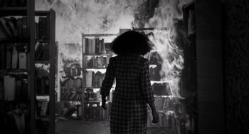 Movie still from “Mood Indigo” (2013), directed by Michel Gondry – A woman standing in front of a burning book shelf; Wide shot, High angle
