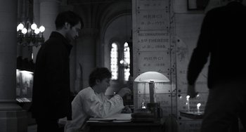 Movie still from “Mood Indigo” (2013), directed by Michel Gondry – A man sitting at a table with a lamp in front of him; Medium shot, Over the shoulder angle
