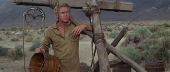 Movie still from “Nevada Smith” (1966), directed by Henry Hathaway – A man leaning against a wooden post in the desert; Medium shot, Low angle