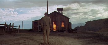 Movie still from “Nevada Smith” (1966), directed by Henry Hathaway – A man standing in front of a burning building; Wide shot, Low angle