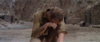 Movie still from “Nevada Smith” (1966), directed by Henry Hathaway – A man sitting on the ground with his head in his hands; Medium shot, Low angle