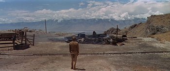 Movie still from “Nevada Smith” (1966), directed by Henry Hathaway – A man standing in front of an abandoned car; Extreme Wide shot, Low angle