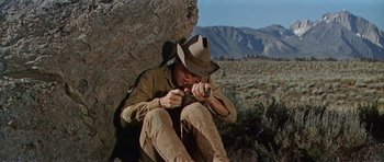 Movie still from “Nevada Smith” (1966), directed by Henry Hathaway – A man sitting on the ground with a hat on; Medium shot, Low angle