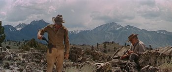 Movie still from “Nevada Smith” (1966), directed by Henry Hathaway – A man standing in the middle of a field with mountains in the background; Wide shot, Low angle