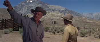 Movie still from “Nevada Smith” (1966), directed by Henry Hathaway – Two men in cowboy hats standing on a dirt field; Medium shot, Low angle