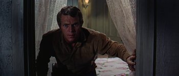 Movie still from “Nevada Smith” (1966), directed by Henry Hathaway – A man standing in front of a curtain in a room; Medium shot, Low angle