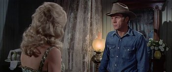 Movie still from “Nevada Smith” (1966), directed by Henry Hathaway – A man in a cowboy hat talking to a woman in a dress; Medium shot, Over the shoulder angle