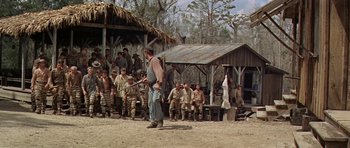 Movie still from “Nevada Smith” (1966), directed by Henry Hathaway – A group of men standing in front of a building; Wide shot, Over the shoulder angle