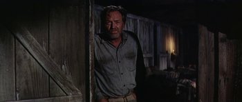 Movie still from “Nevada Smith” (1966), directed by Henry Hathaway – A man standing next to a wall in a dark room; Medium shot, Low angle
