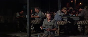 Movie still from “Nevada Smith” (1966), directed by Henry Hathaway – A group of men sitting on top of a wooden bench; Wide shot, High angle