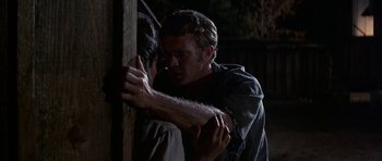 Movie still from “Nevada Smith” (1966), directed by Henry Hathaway – A man holding another man's hand while he leans against a wooden pole; Close Up shot, Over the shoulder angle
