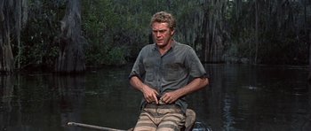 Movie still from “Nevada Smith” (1966), directed by Henry Hathaway – A man standing on a raft in a body of water; Medium shot, Over the shoulder angle