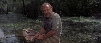 Movie still from “Nevada Smith” (1966), directed by Henry Hathaway – An older man sitting on the ground in the woods; Medium shot, High angle