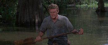 Movie still from “Nevada Smith” (1966), directed by Henry Hathaway – A man holding a paddle in a body of water; Medium shot, Over the shoulder angle