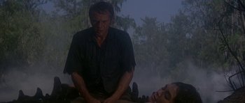Movie still from “Nevada Smith” (1966), directed by Henry Hathaway – A man sitting next to a dead body in the rain; Medium shot, Low angle