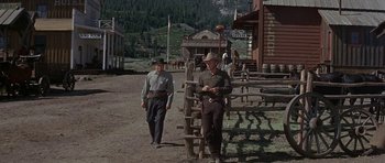 Movie still from “Nevada Smith” (1966), directed by Henry Hathaway – Two men are standing in front of a wooden fence; Wide shot, Low angle