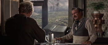 Movie still from “Nevada Smith” (1966), directed by Henry Hathaway – Two men sitting at a table in front of a window; Medium shot, Over the shoulder angle
