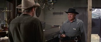 Movie still from “Nevada Smith” (1966), directed by Henry Hathaway – A man in a cowboy hat is talking to another man; Medium shot, Over the shoulder angle