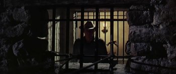 Movie still from “Nevada Smith” (1966), directed by Henry Hathaway – A man wearing a cowboy hat sitting in a jail cell; Medium shot, Low angle