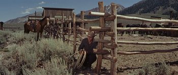 Movie still from “Nevada Smith” (1966), directed by Henry Hathaway – A man kneeling down next to a wooden fence; Wide shot, Low angle