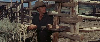 Movie still from “Nevada Smith” (1966), directed by Henry Hathaway – A man wearing a cowboy hat standing in front of a fence; Medium shot, Low angle